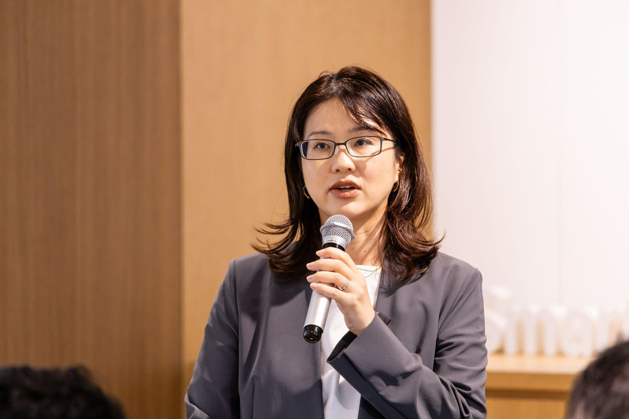 イベントに登壇し、マイクを握って説明をする眼鏡をかけた松栄さん