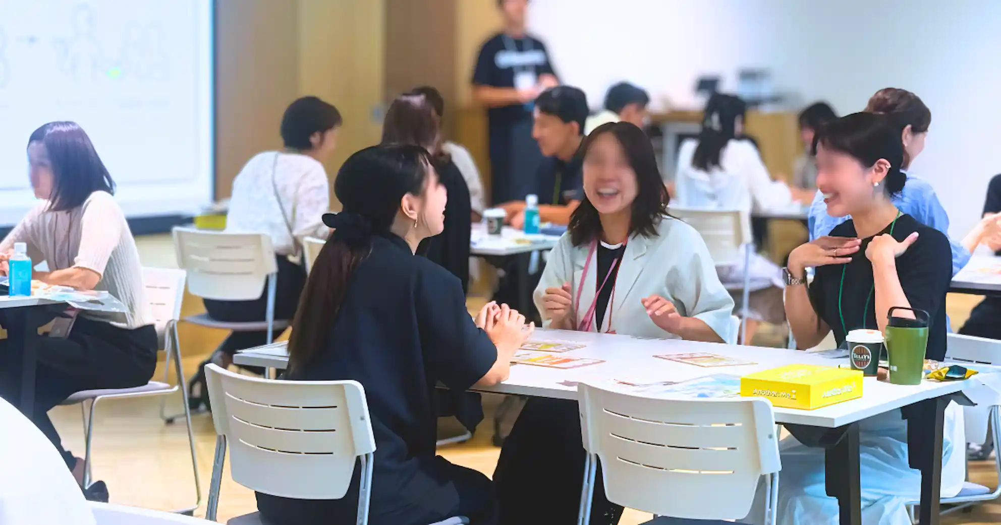 会場のテーブルを囲み、机上のカードなどを前に笑顔で会話をするイベント参加者たちの様子