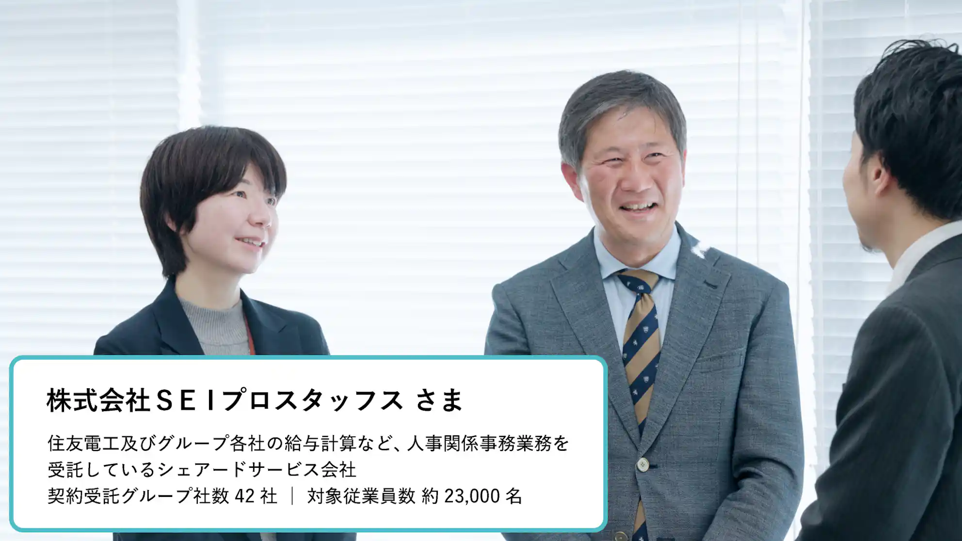 株式会社SEIプロスタッフスさまの紹介。笑顔で話す3人のビジネスパーソンと、住友電工グループの給与計算など人事関係事務業務を受託しているシェアードサービス会社であること、契約受託グループ社数42社、対象従業員数約23,000名という実績テキスト。