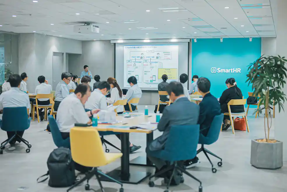 参加者が講演を見にプレゼンテーションを聞く様子