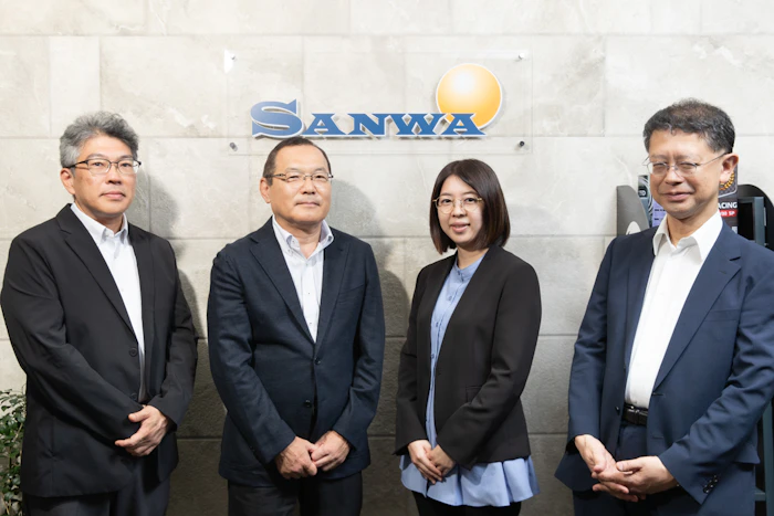三和化成工業株式会社のSmartHR導入に関する事例記事のアイキャッチ画像。会社の看板を背景に、4人のインタビュイーが横一列に並んでいる。