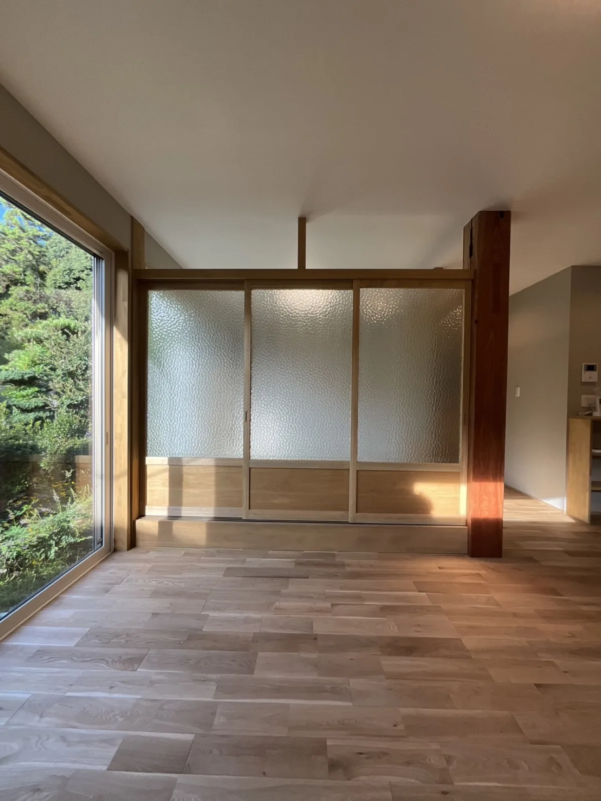 型板ガラスの引き戸から光が回る平屋の室内