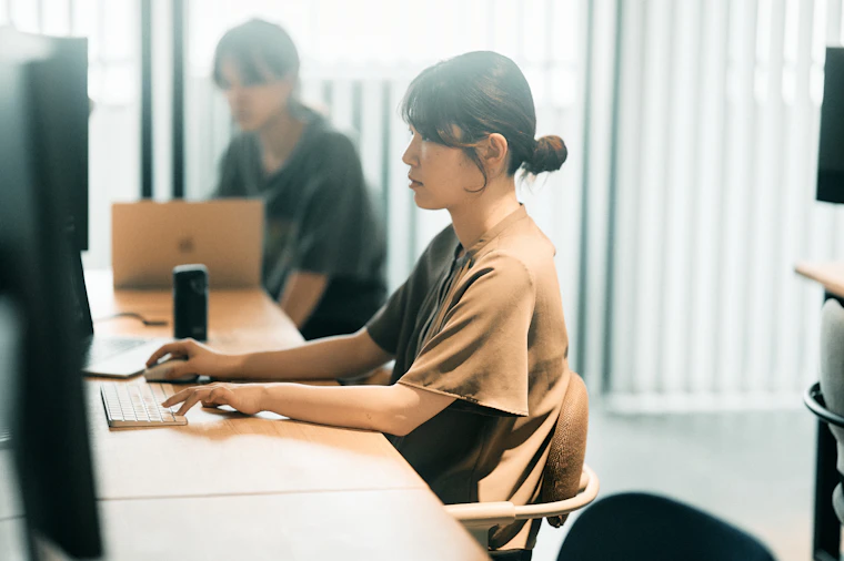オフィスでモニターに向かい作業する丸山