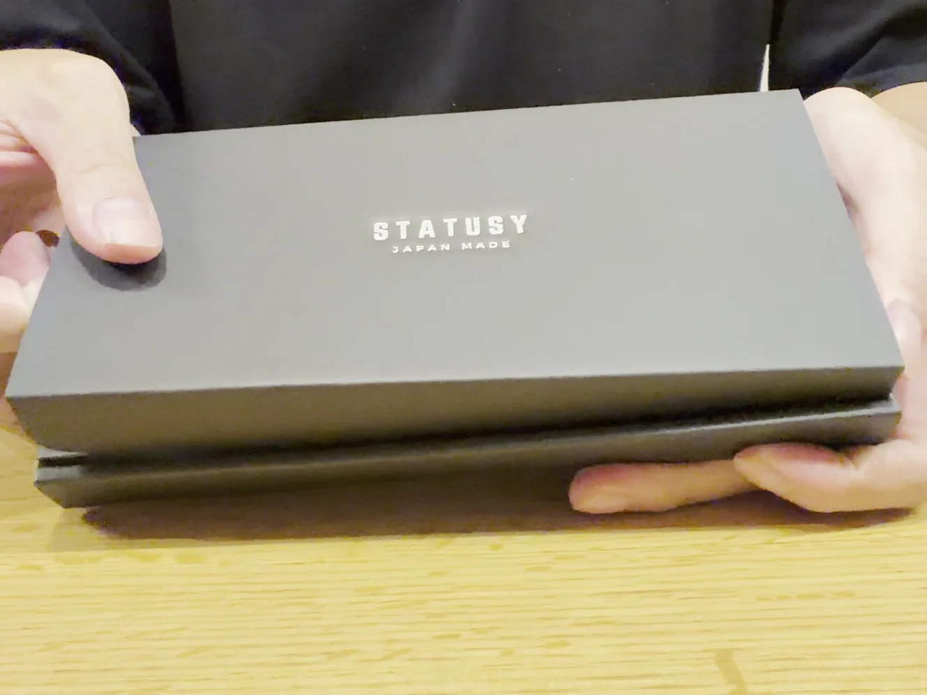 「STATUSY JAPAN MADE」と押された黒い外箱を手に持ったところ
