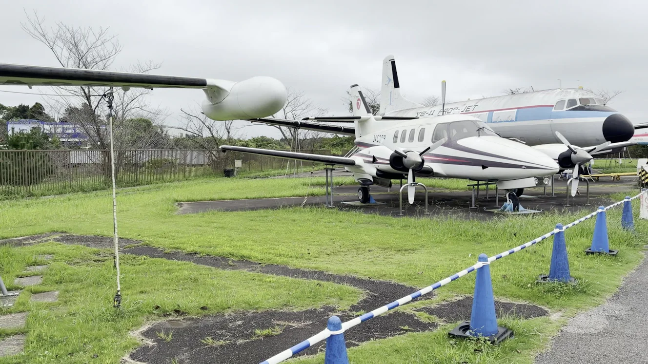 航空科学博物館の屋外展示場。手前にMU-2の主翼、奥に双発のプロペラ機と、胴体に「YS-11 PROP-JET」と書かれたYS-11が並んでいる