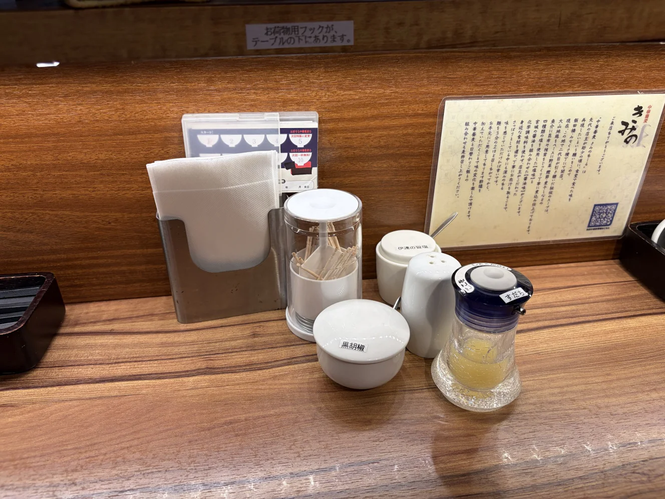 カウンターの卓上に並ぶ黒胡椒と白胡椒、伊達の旨塩、そして液体の入ったすだちのディスペンサー