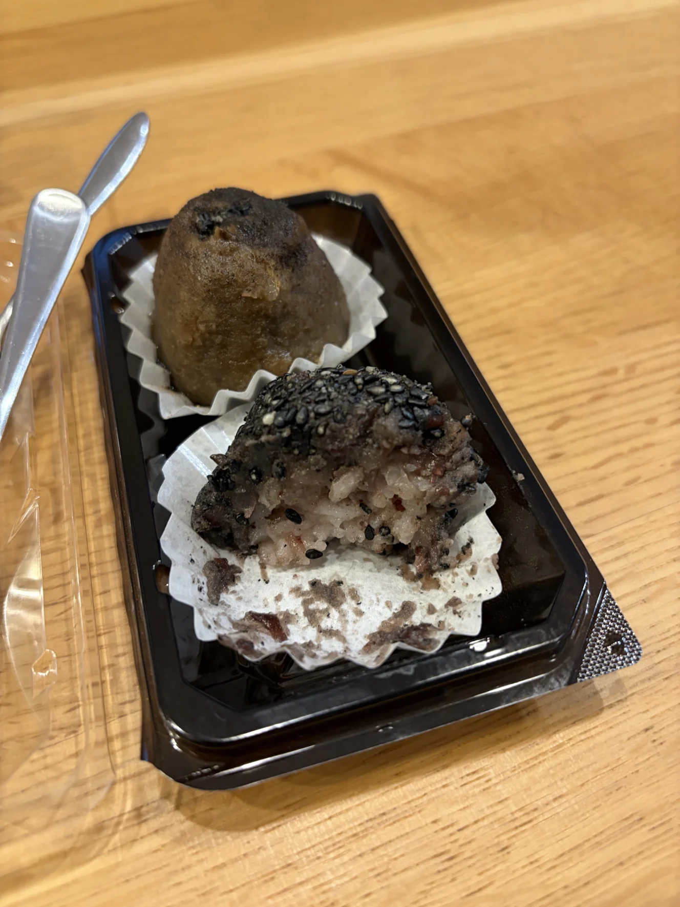 半分に割った黒ゴマのおはぎの断面。外側に黒ゴマがびっしり付き、中は粒の粗い雑穀米