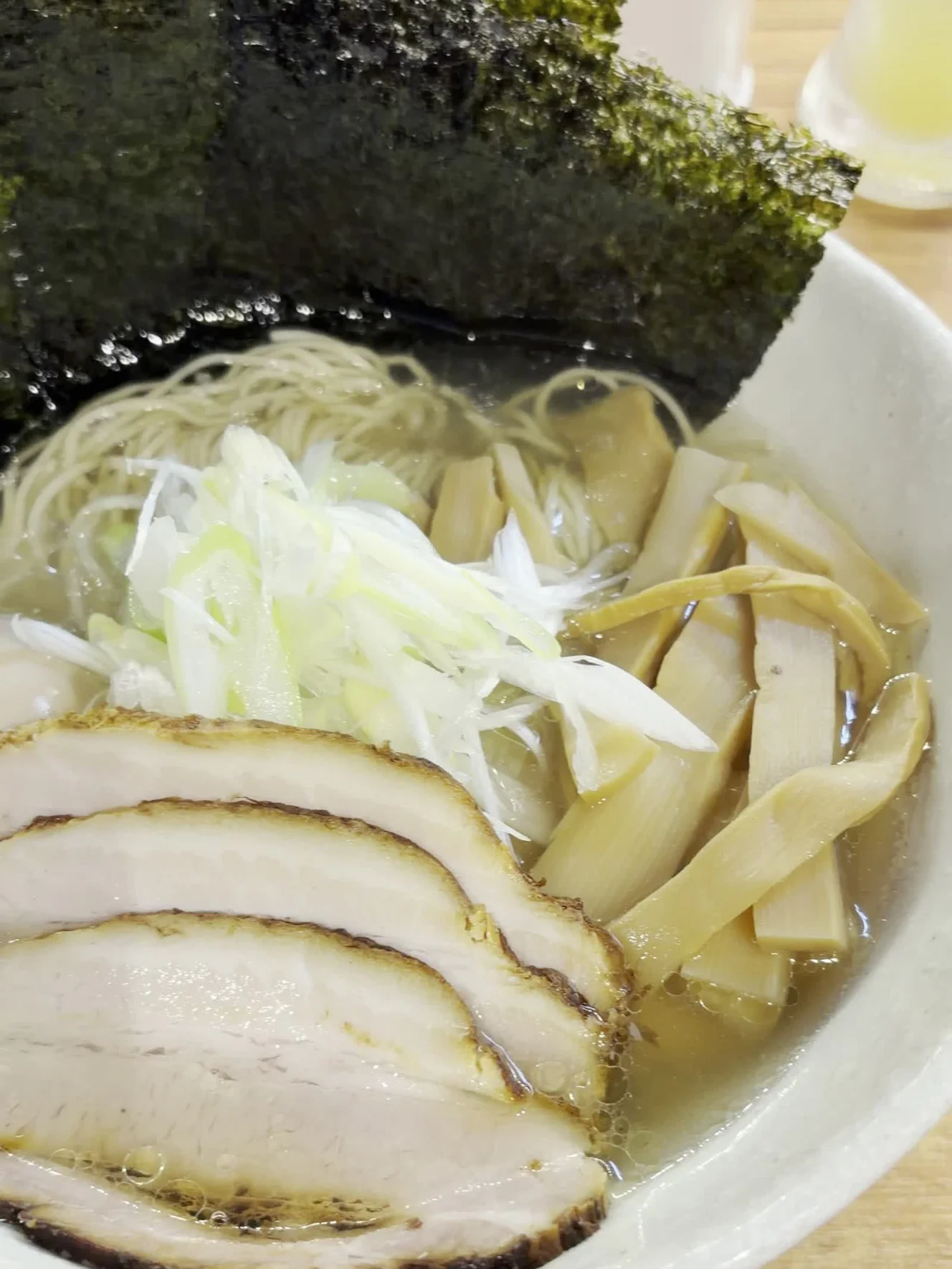 特製・塩1,300円の丼。海苔、さらしネギ、チャーシュー、メンマが澄んだスープに載り、奥にすだちのディスペンサーが見える