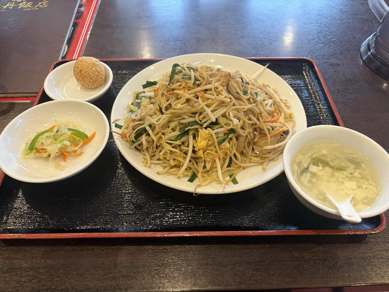 玉子焼きそばのトレー。焼きそばの大皿と、サラダの小皿、ごま団子、玉子スープ