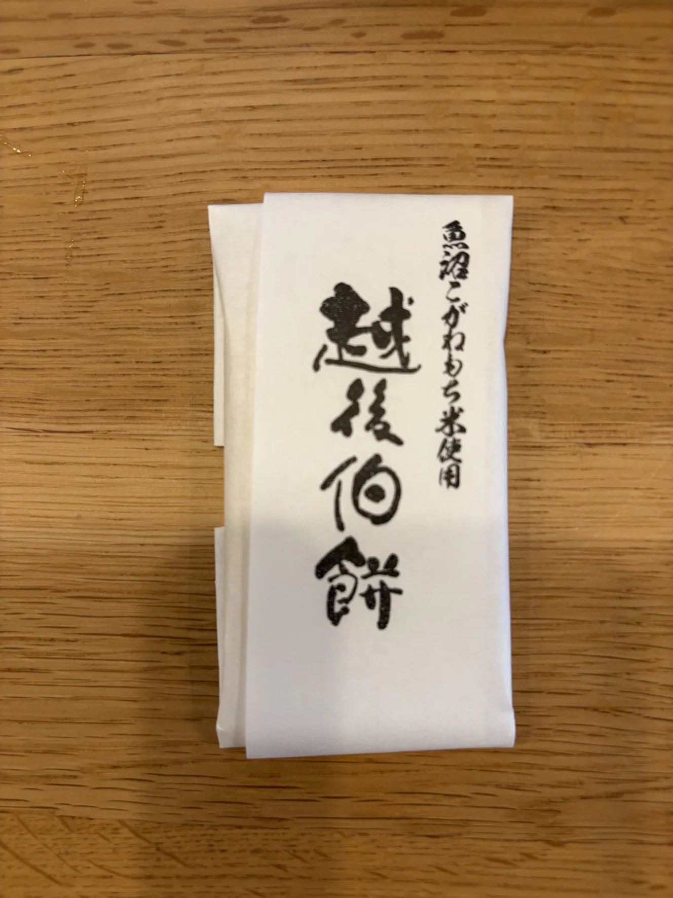 白い紙で四角く包まれた越後伯餅の個包装