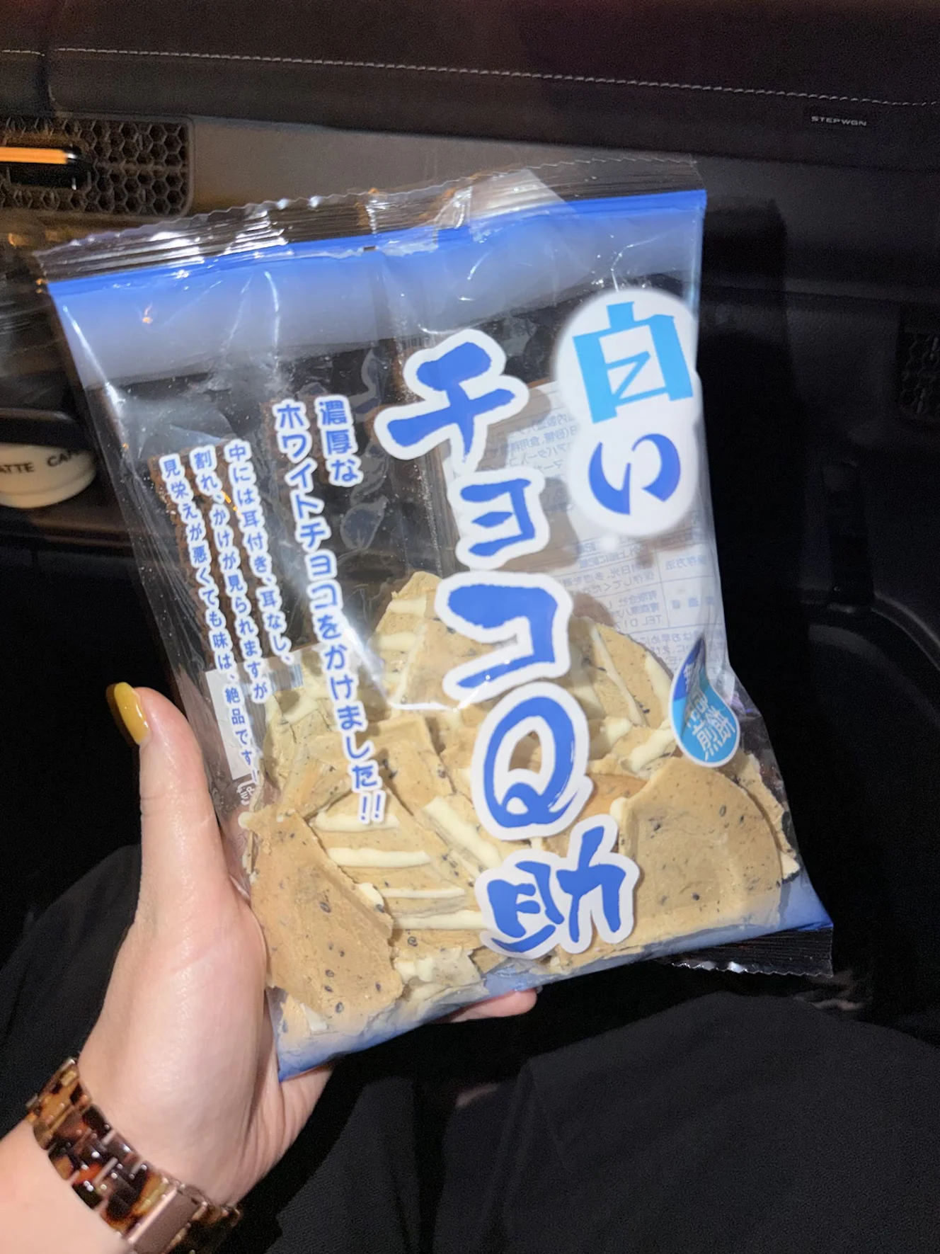 車内で妻が持った白いチョコQ助の袋。青い文字が入った透明の袋に、ホワイトチョコがかかった割れ煎餅が入っている