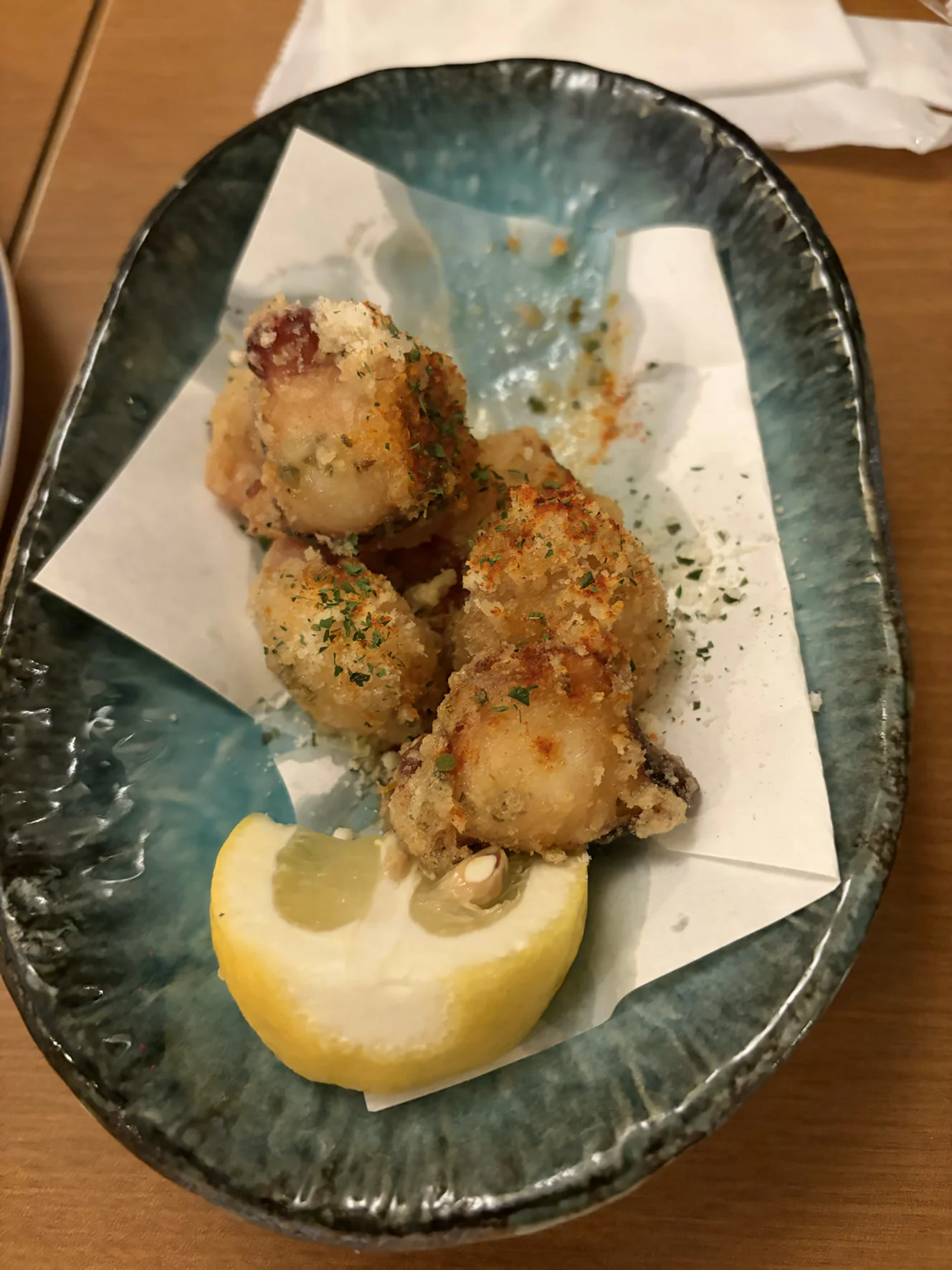 青い皿に盛られた大判のたこの唐揚げとレモン