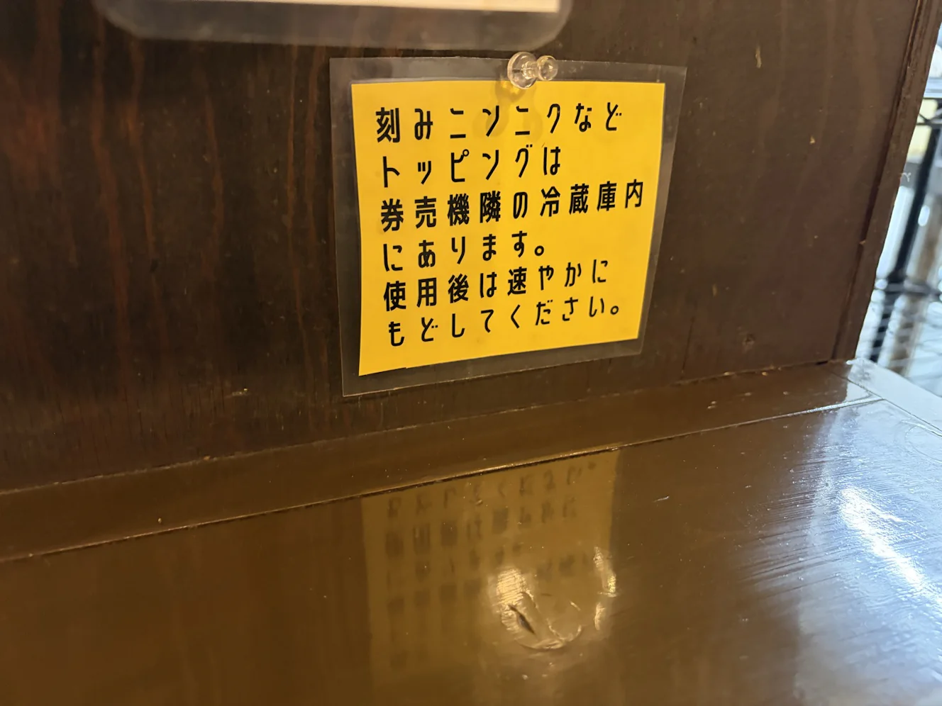 店内の黄色い掲示。「刻みニンニクなどトッピングは券売機隣の冷蔵庫内にあります。使用後は速やかにもどしてください」と書かれている