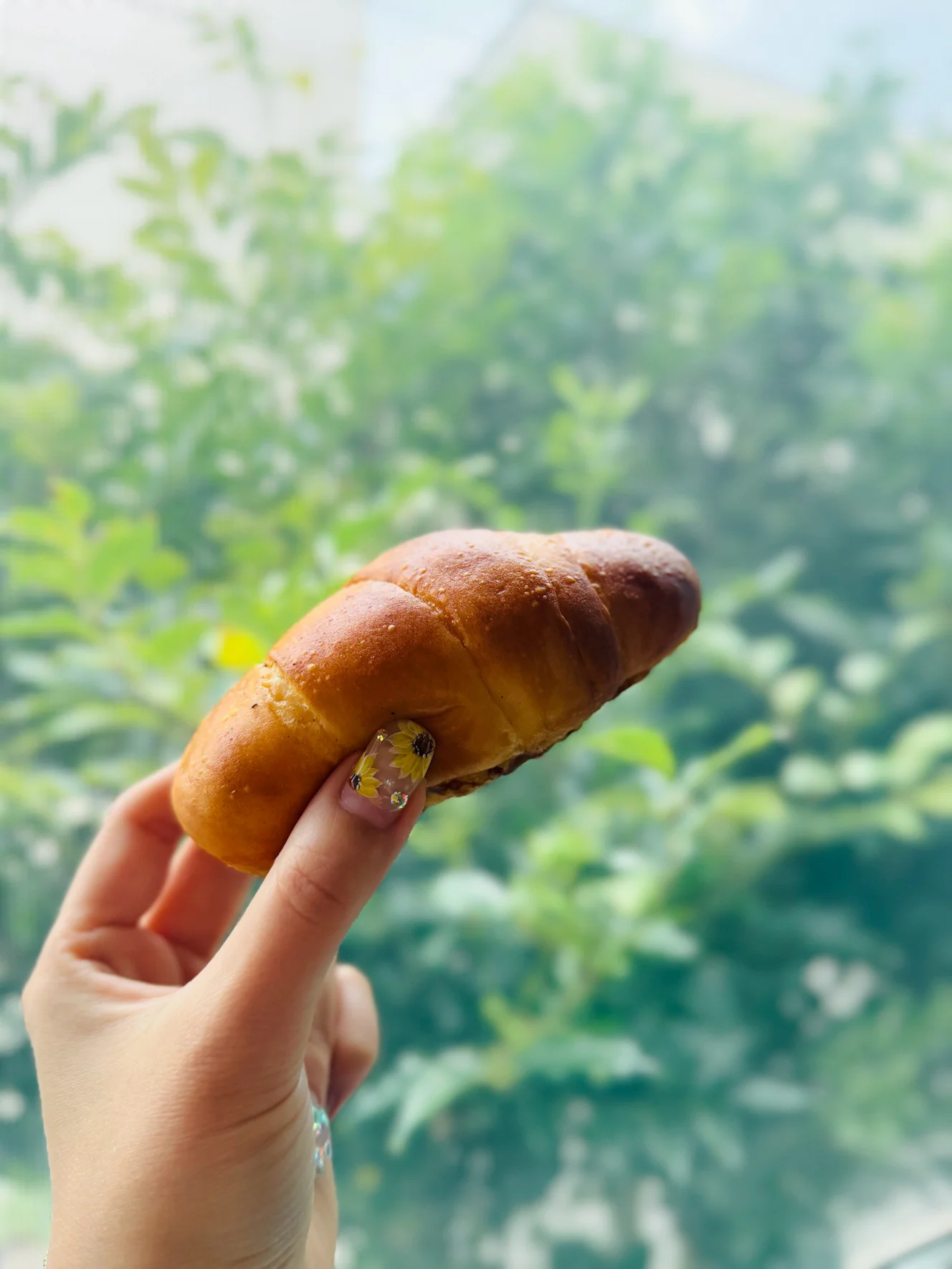手に持った塩パン。細長いロール型で、つやのある濃い焼き色がついている
