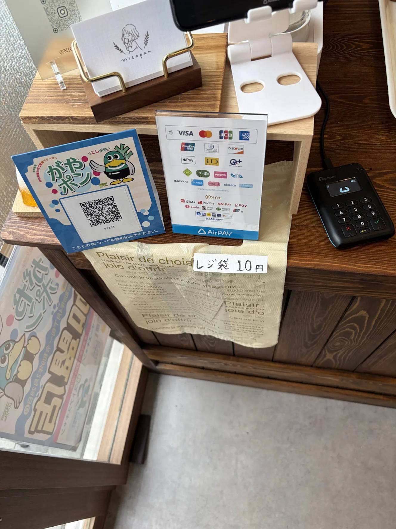 パン屋nicopanのレジ横に並ぶ、がやポンのQRコードスタンドとAirPAYの決済案内板
