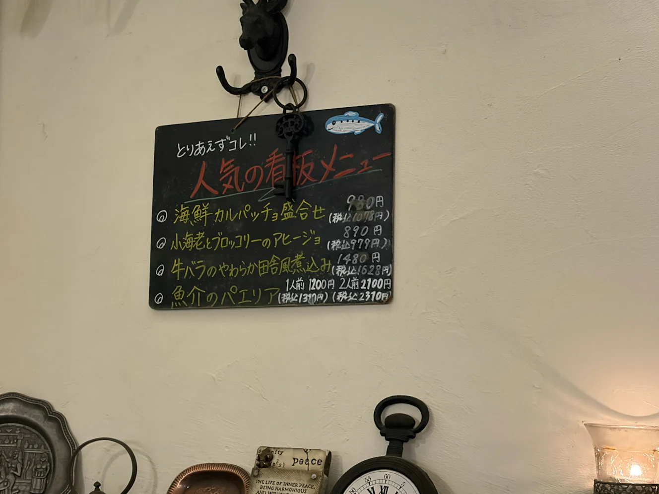 壁の黒板「とりあえずコレ!! 人気の看板メニュー」。4品と価格が手書きされている