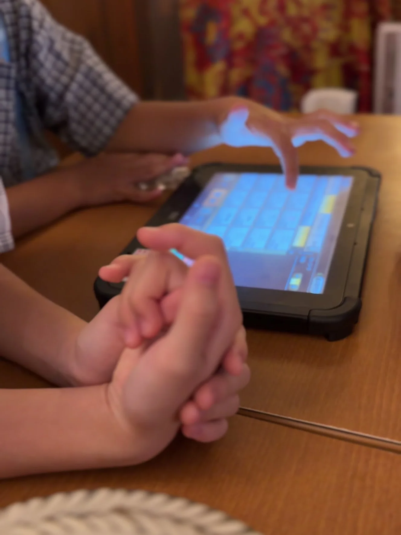 席のタブレットを操作する子どもの手元