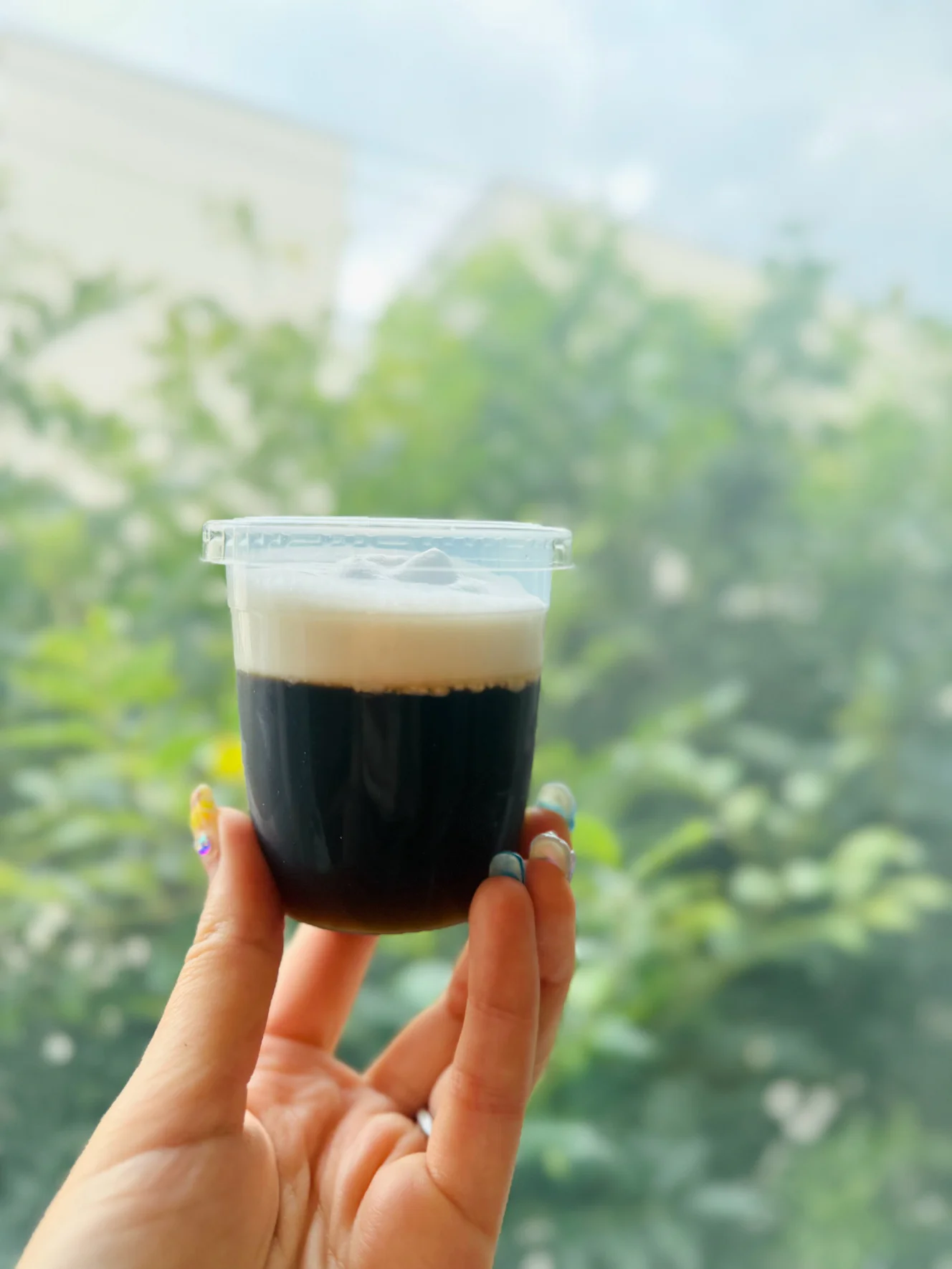 ふた付きの透明カップに入ったコーヒーゼリー。黒いゼリーの上に白いクリームの層がのっている