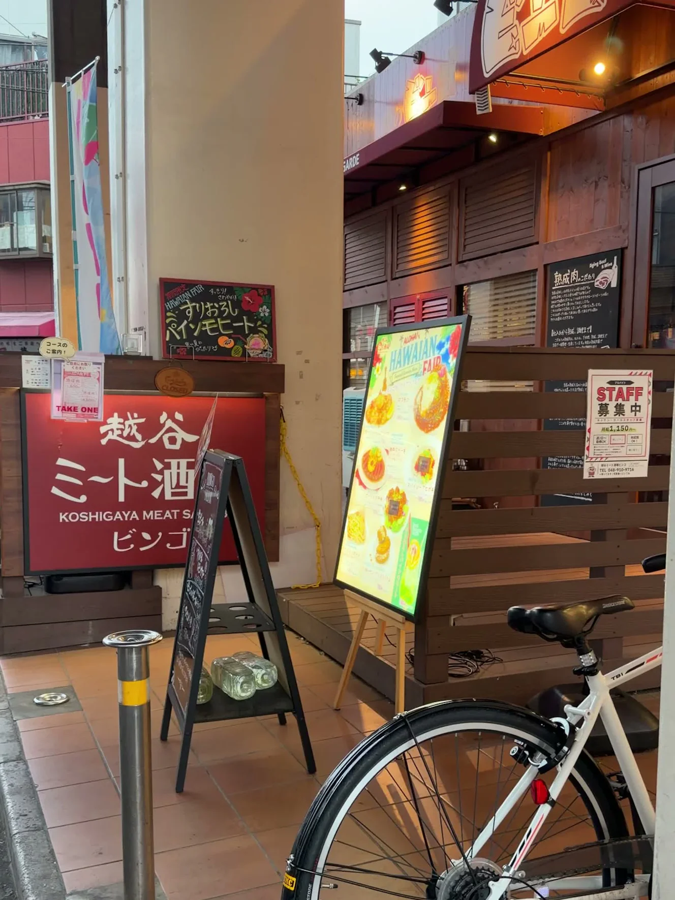 越谷ミート酒場 ビンゴの外観と、通り沿いに出た赤い看板