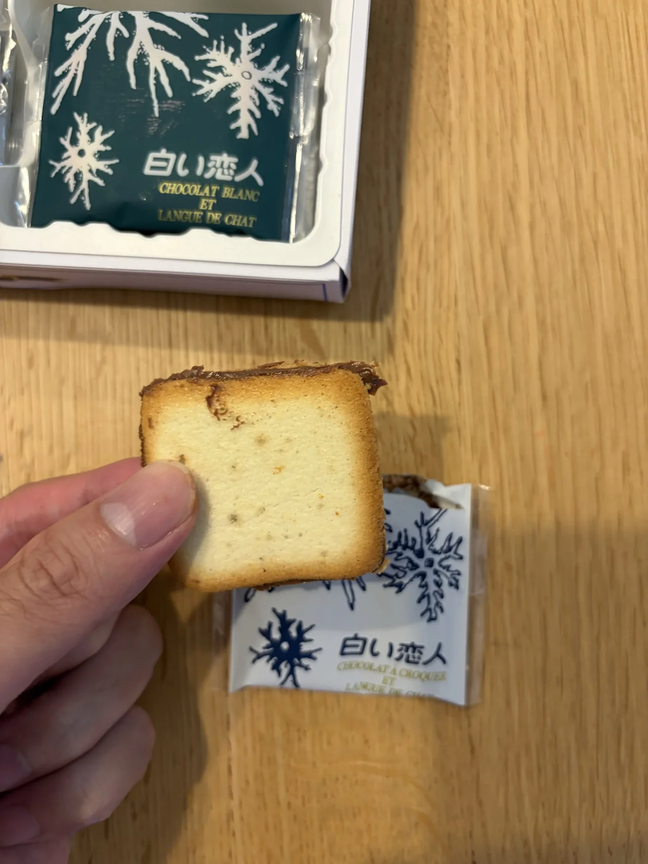 白い恋人のブラック。ラング・ド・シャの間に茶色いチョコレート。手前の白い個包装にCHOCOLAT A CROQUERの表記