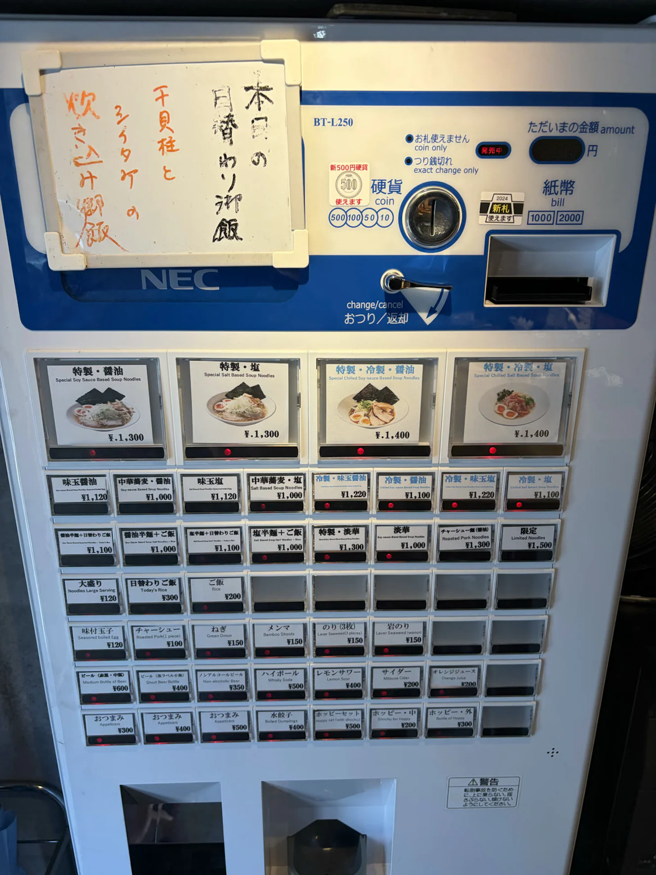 店内の券売機。上部に「本日の日替わり御飯 干貝柱とシイタケの炊き込み御飯」の手書きの札が貼られている