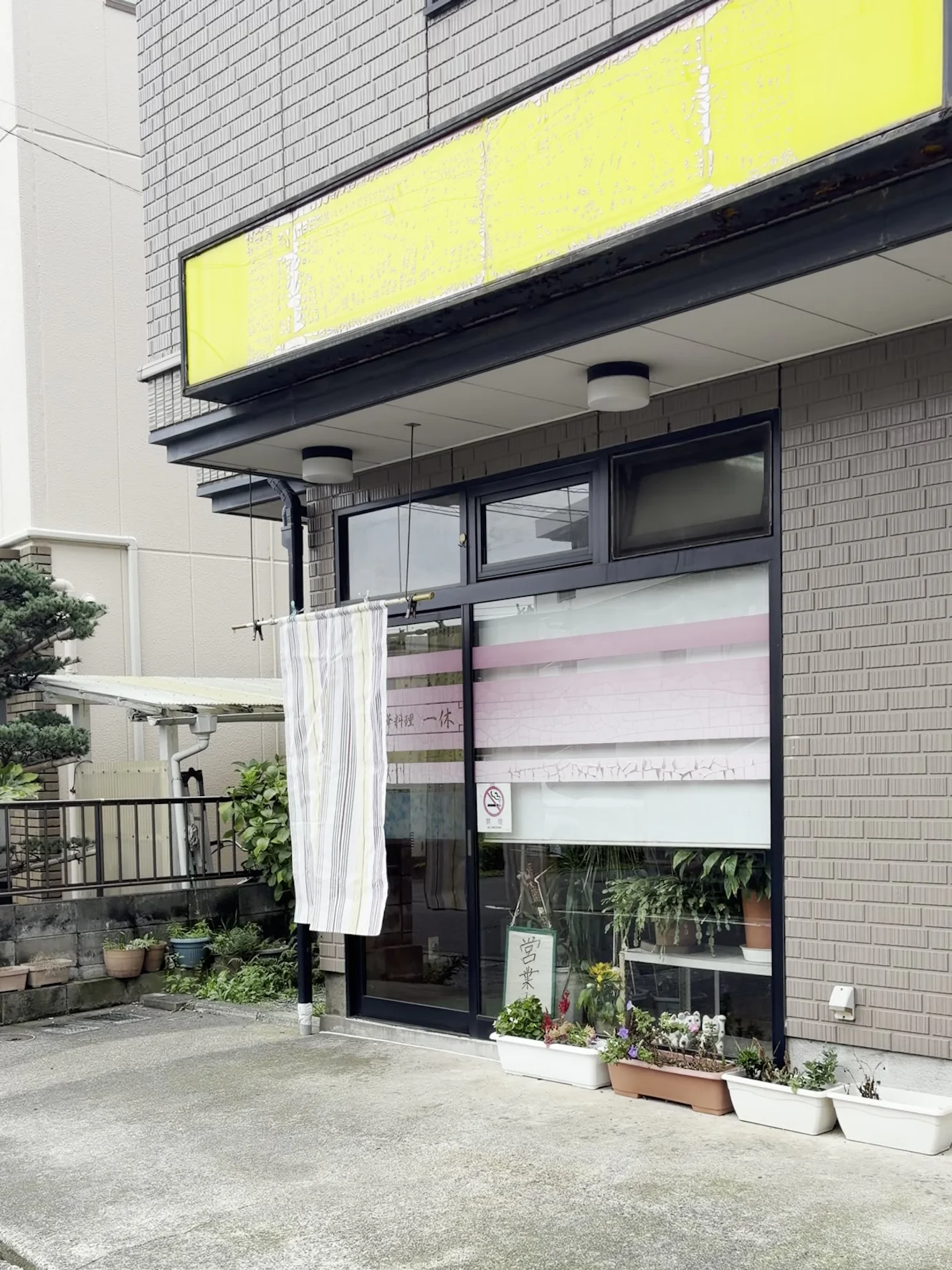 中華料理一休の外観。黄色い看板の下に白い暖簾が下がり、ガラスの引き戸が入口になっている