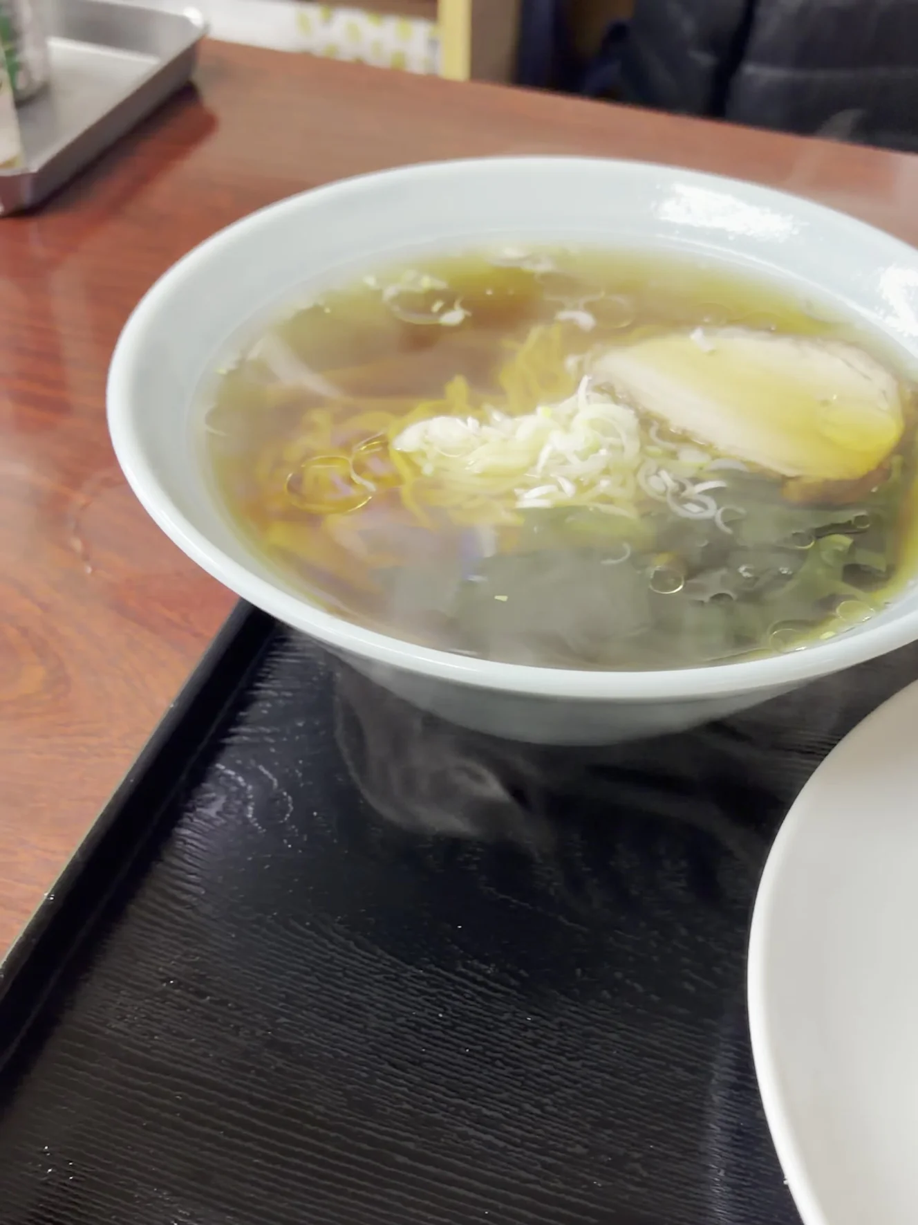 半ラーメンの丼。澄んだしょうゆのスープに、チャーシューとわかめ、ねぎが載っている