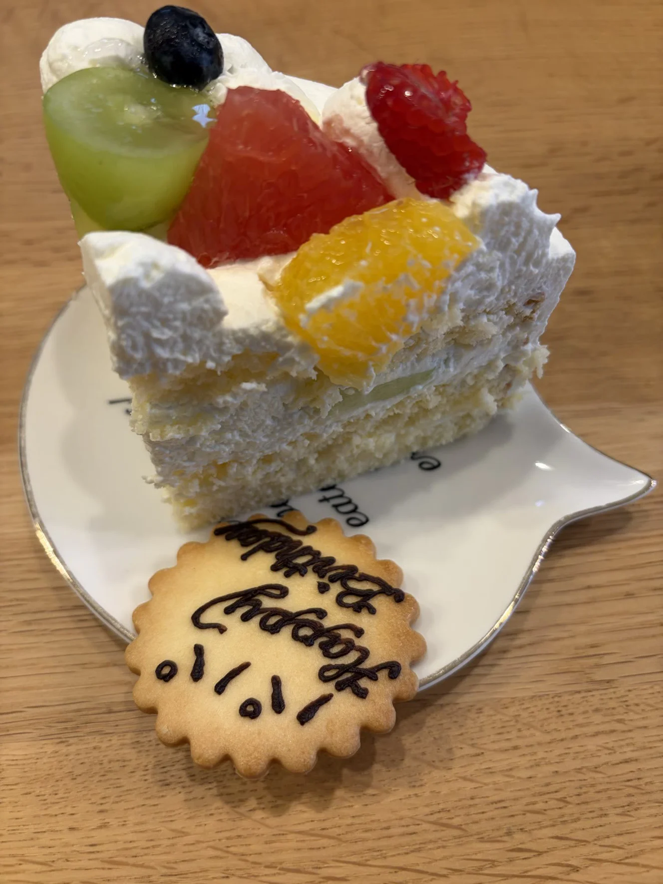 切り分けたひと切れの断面。スポンジの間に生クリームとメロンの薄切りが挟まり、上にフルーツが乗っている