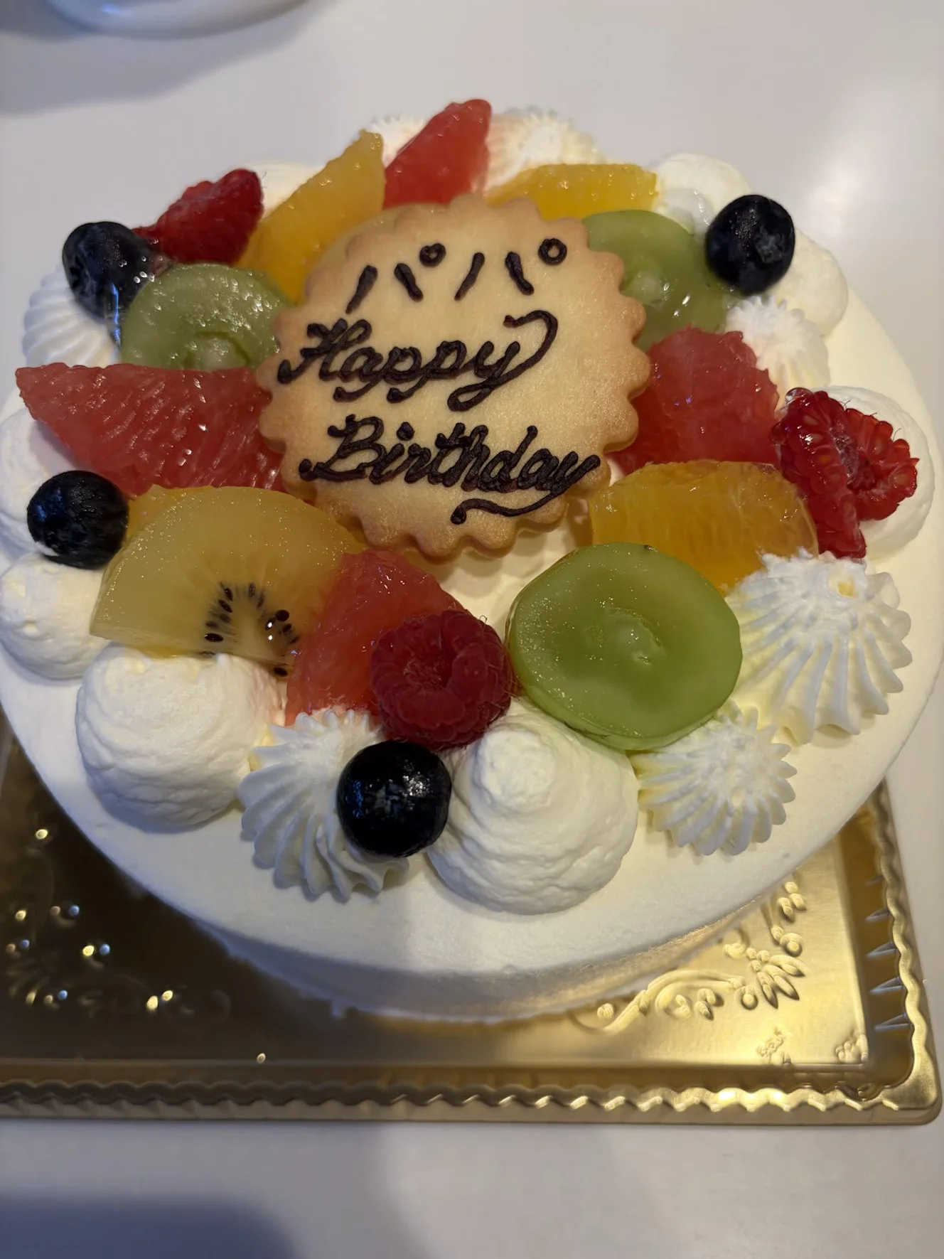 「パパ Happy Birthday」のクッキープレートを載せた5号のホールケーキ。金色の台に乗っている