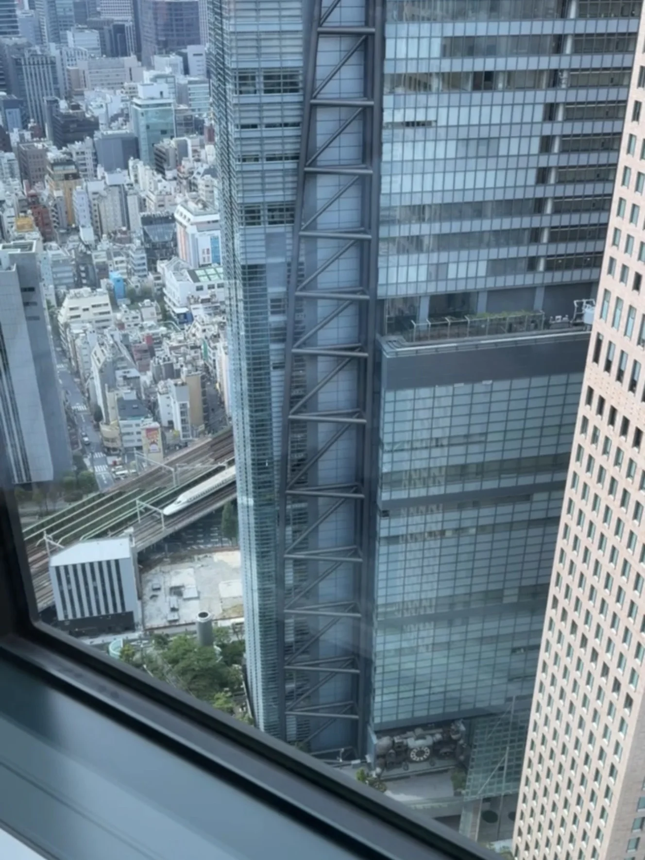 客室の窓から見えた眺め。高層ビルの下を新幹線が走っている