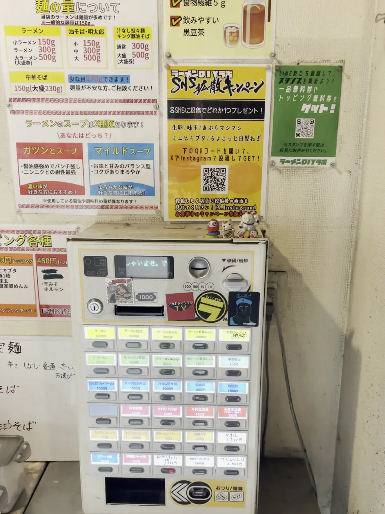 券売機と、その上の壁の掲示。「麺の量について」「ラーメンのスープは2種類あります」などの掲示が貼られている