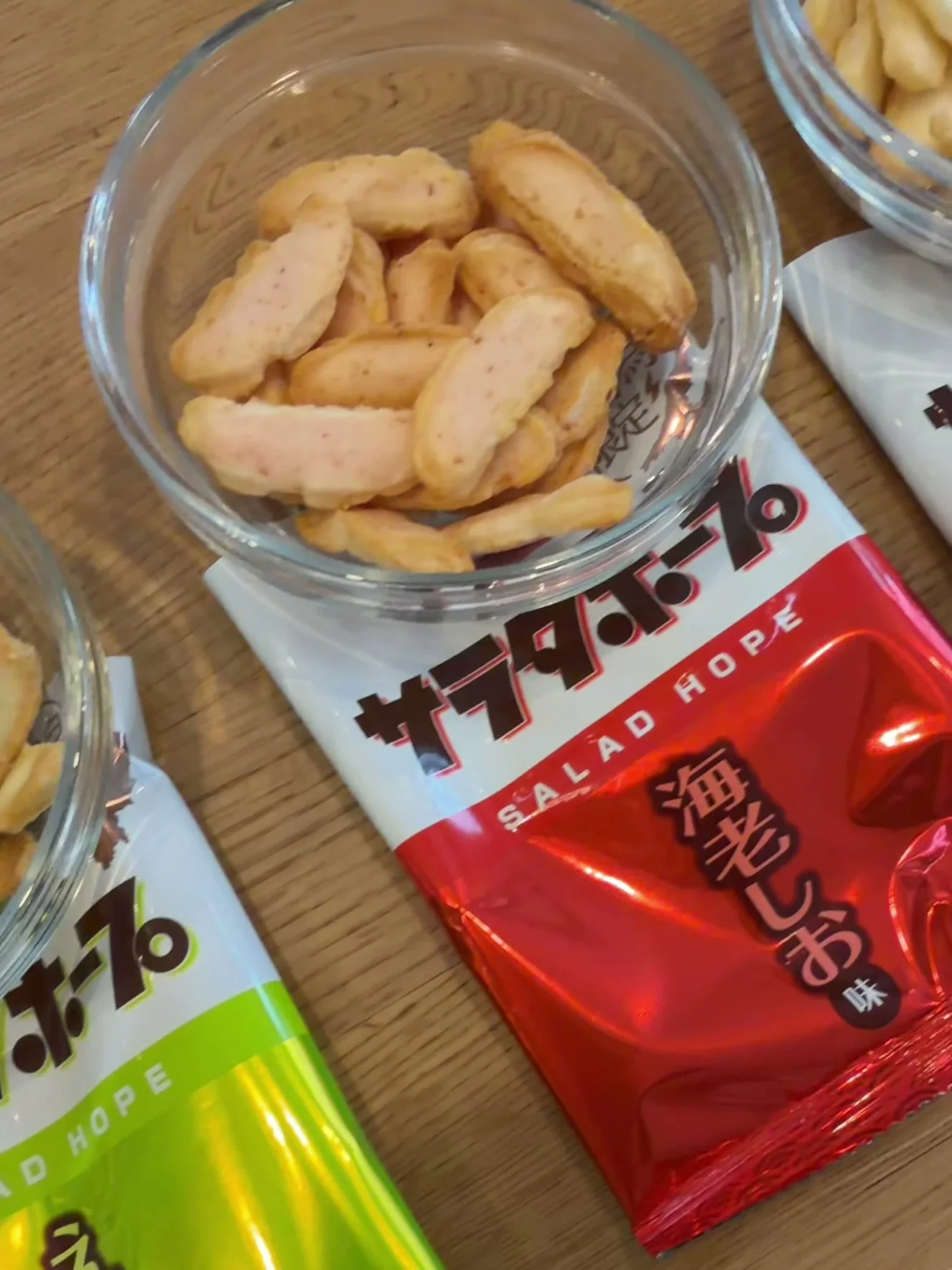 ガラスの器に出した海老しお味のあられ。赤い海老しお味の小袋の上に器が乗っている