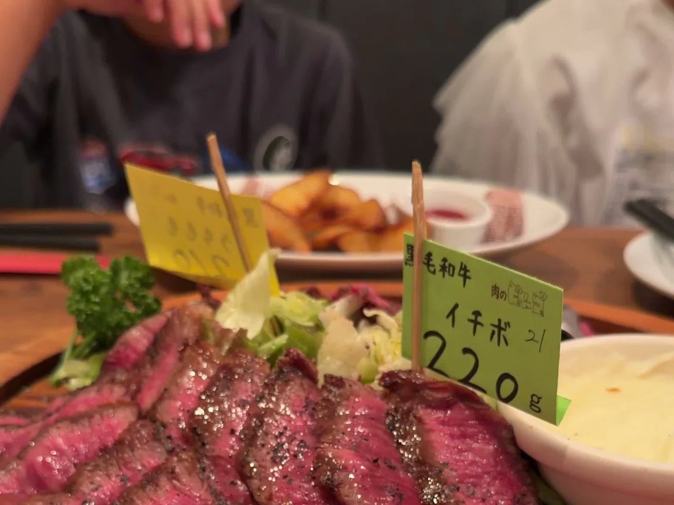 1枚の大皿に半分ずつ盛られた熟成肉。部位の札とマッシュポテトが添えられている