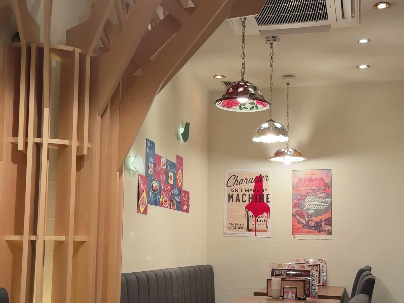 木を組んだ柱と花柄のペンダント照明が並ぶ店内のテーブル席