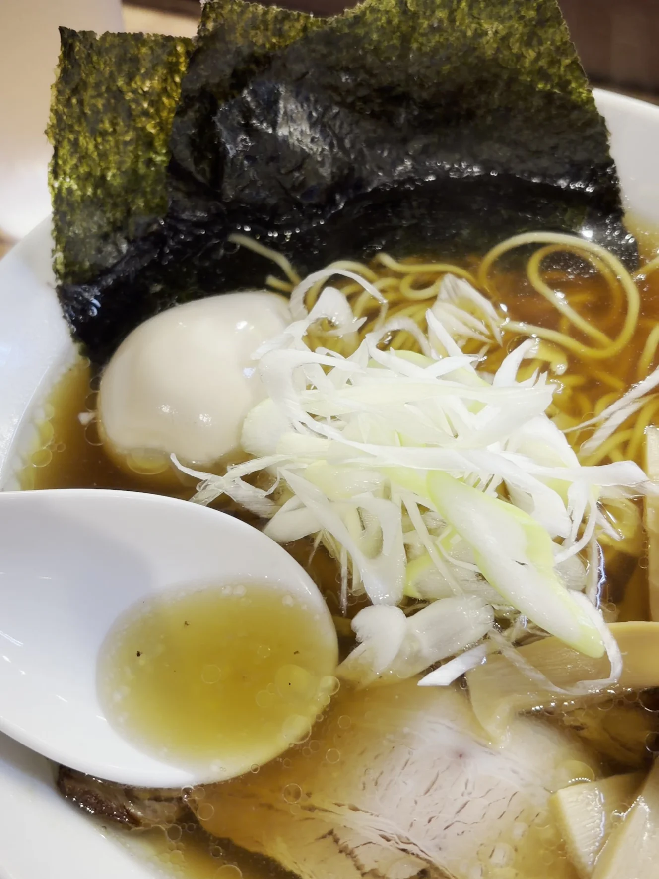 レンゲにすくった醤油スープ。濁りがほとんどなく、底が透けて見える