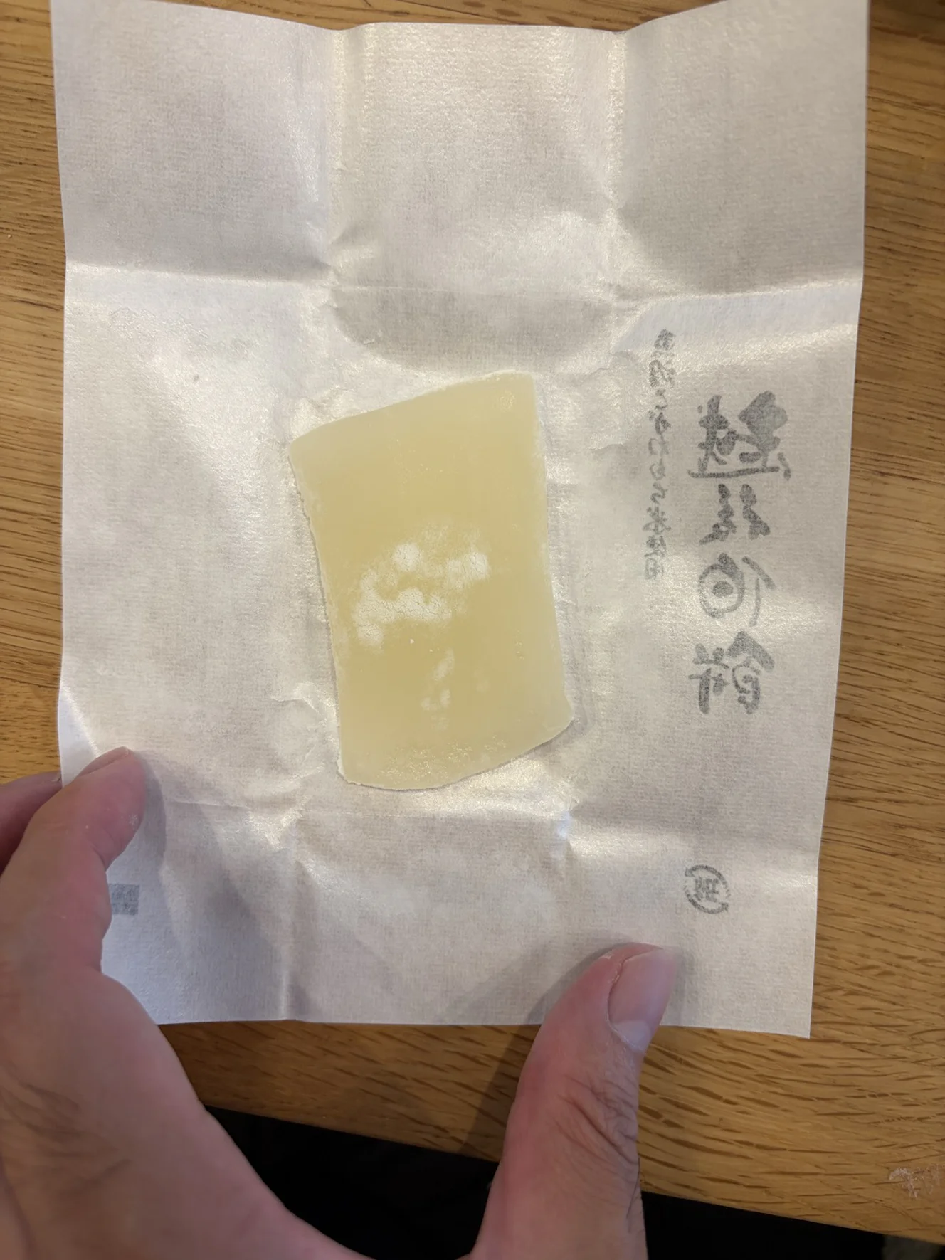 包み紙を開いた淡いクリーム色の餅。表面に白い粉がまだらに付いている