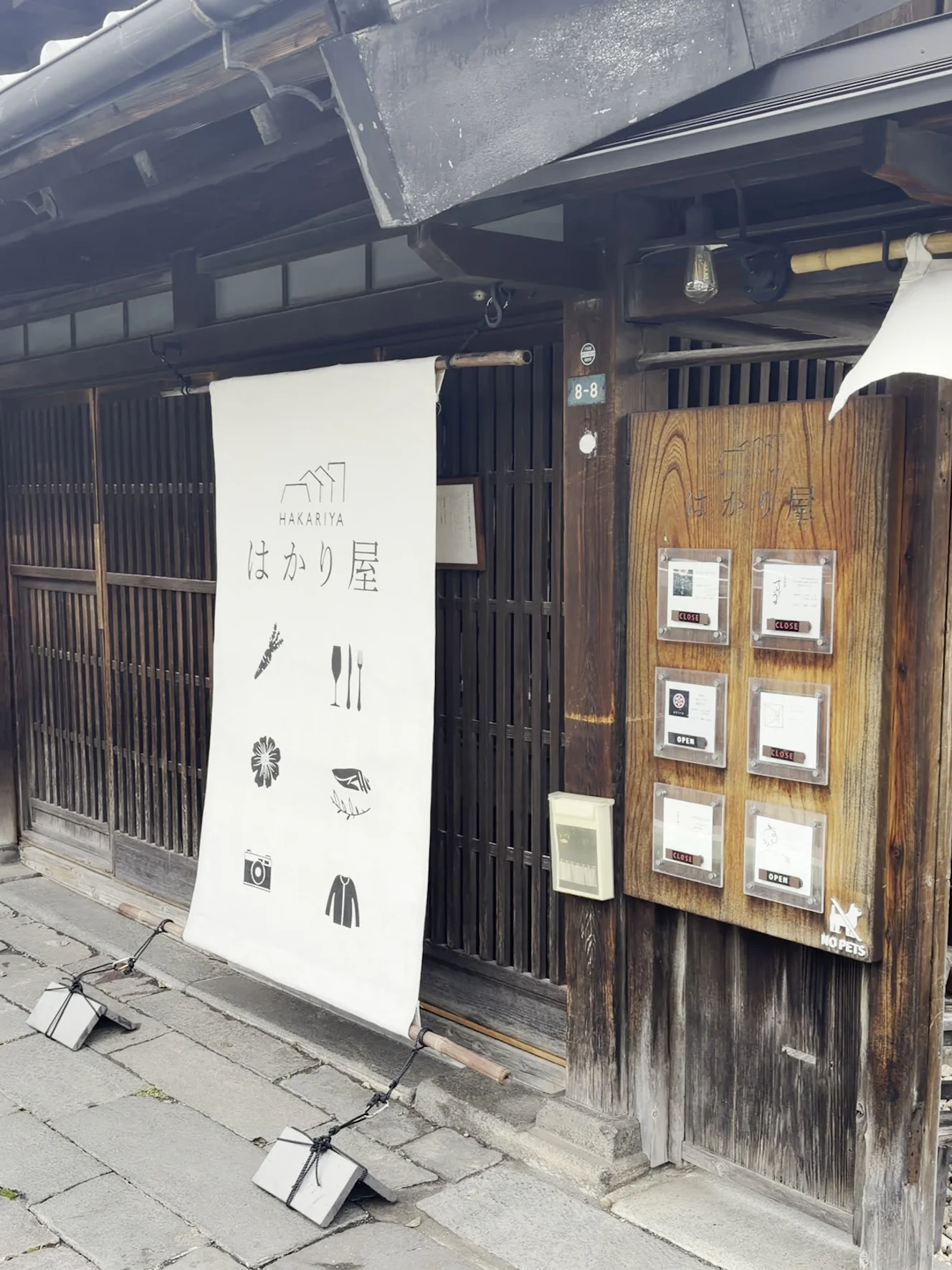 はかり屋の入口。白い暖簾と木の掲示板