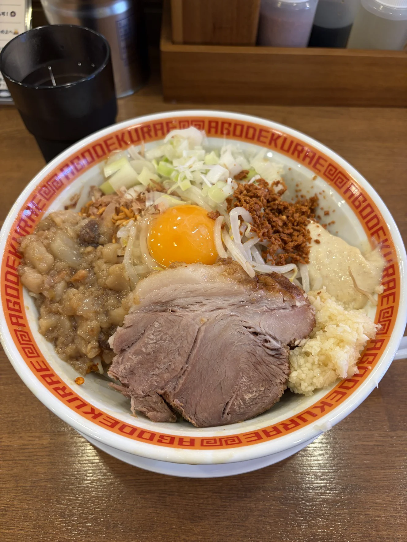 顎で喰らえのまぜそば(並)。中央に生卵の黄身、厚いチャーシュー2枚、背脂・刻みねぎ・もやし・刻みニンニクが盛られている