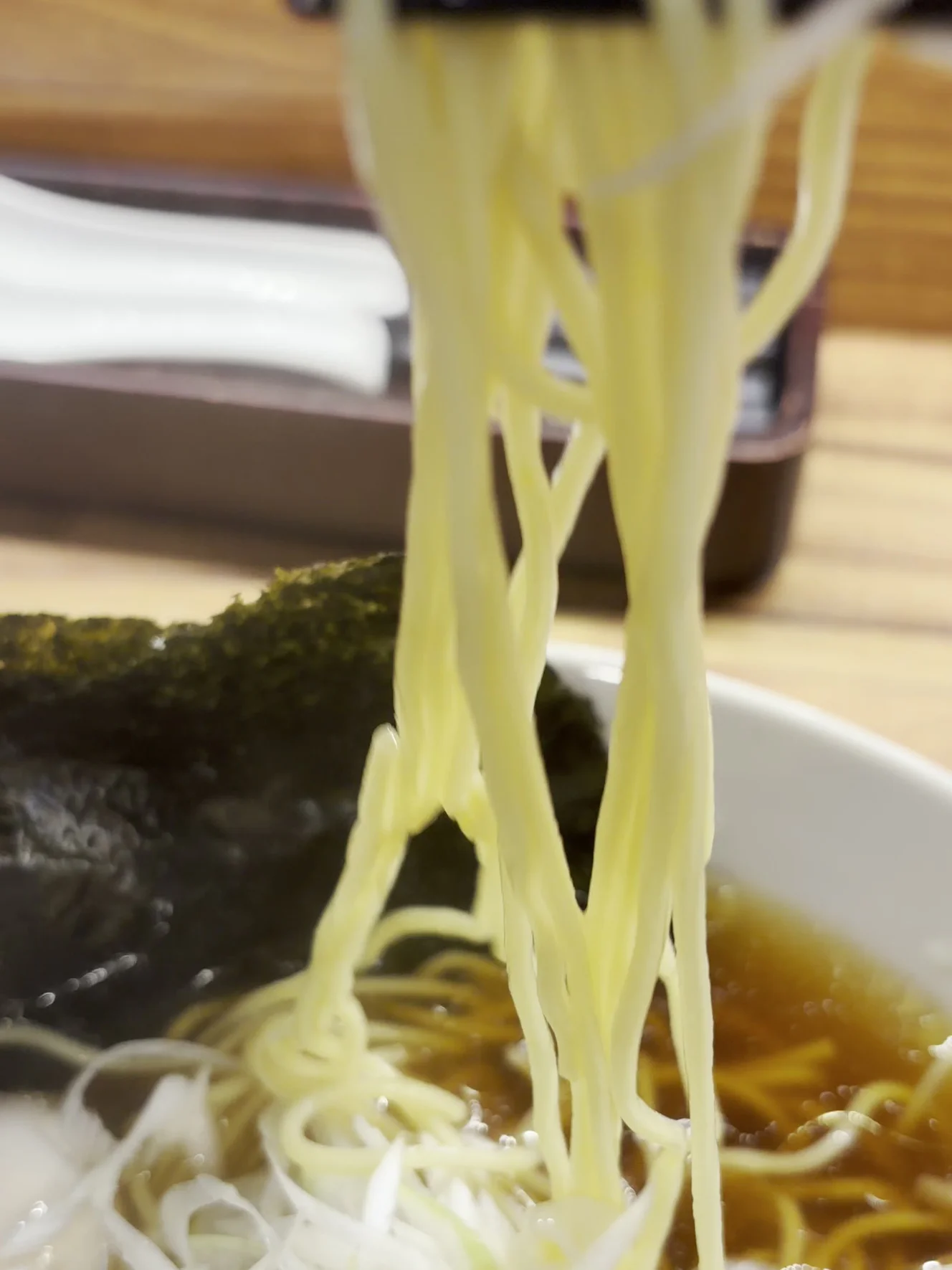 箸で持ち上げた麺。まっすぐで、表面がなめらかに光っている