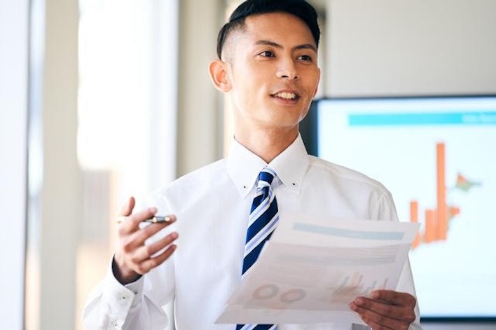 グラフを指さしてプレゼンテーションをする男性