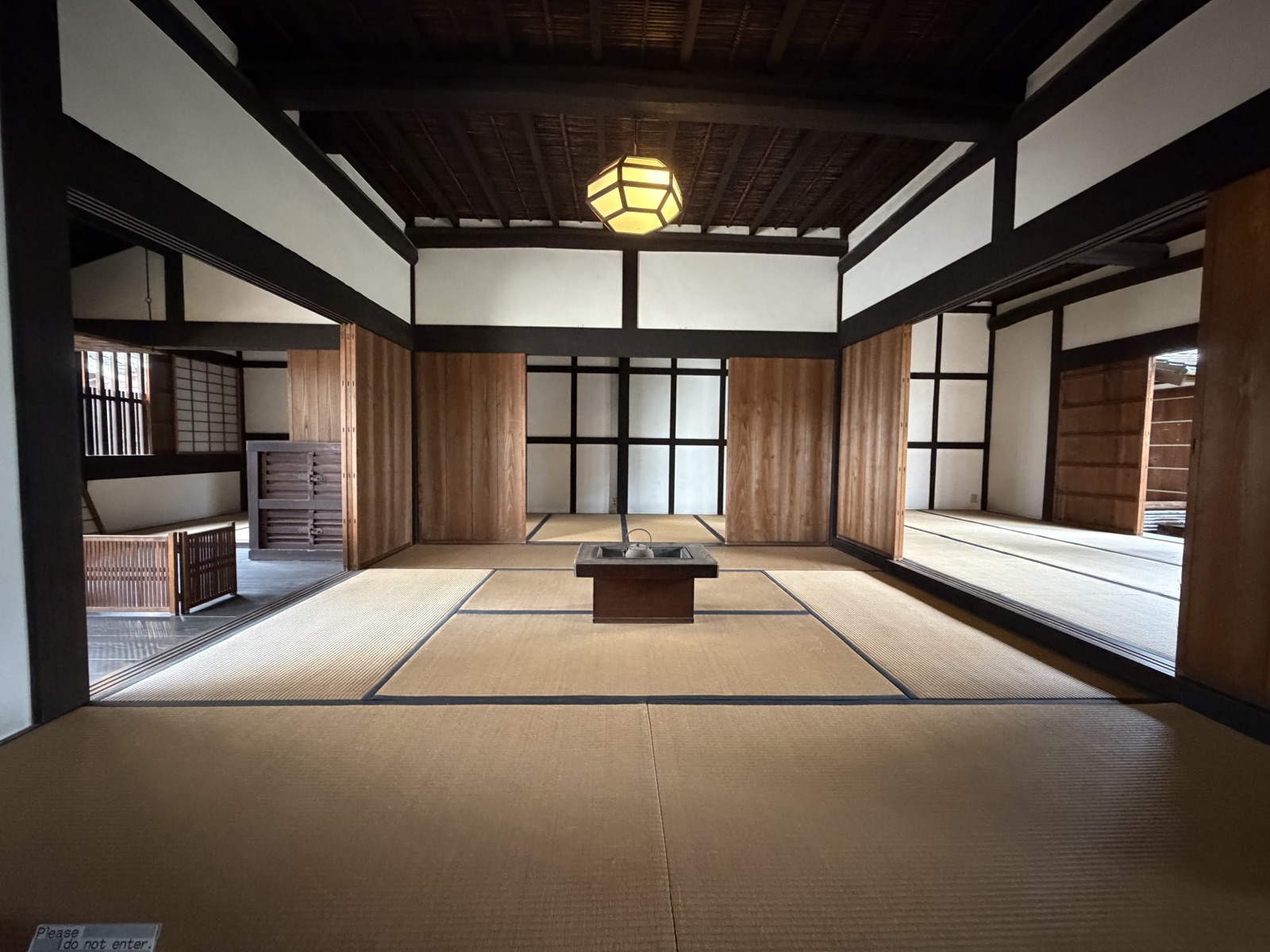 畳敷きの広い座敷。中央に四角い囲炉裏が据えられ、天井から六角形の和紙の照明が下がる