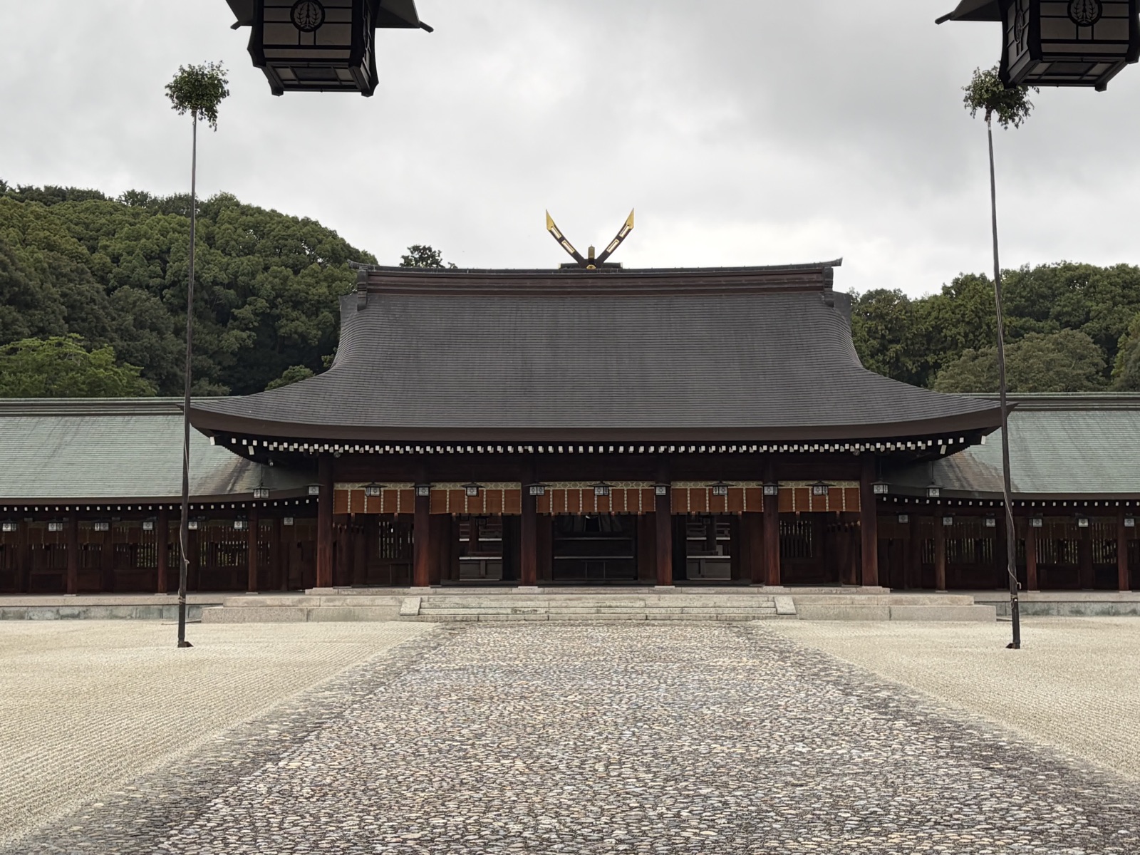 玉砂利の参道の正面に構える橿原神宮の外拝殿。濃い茶色の柱と反りのある大屋根、棟の上に金色の千木