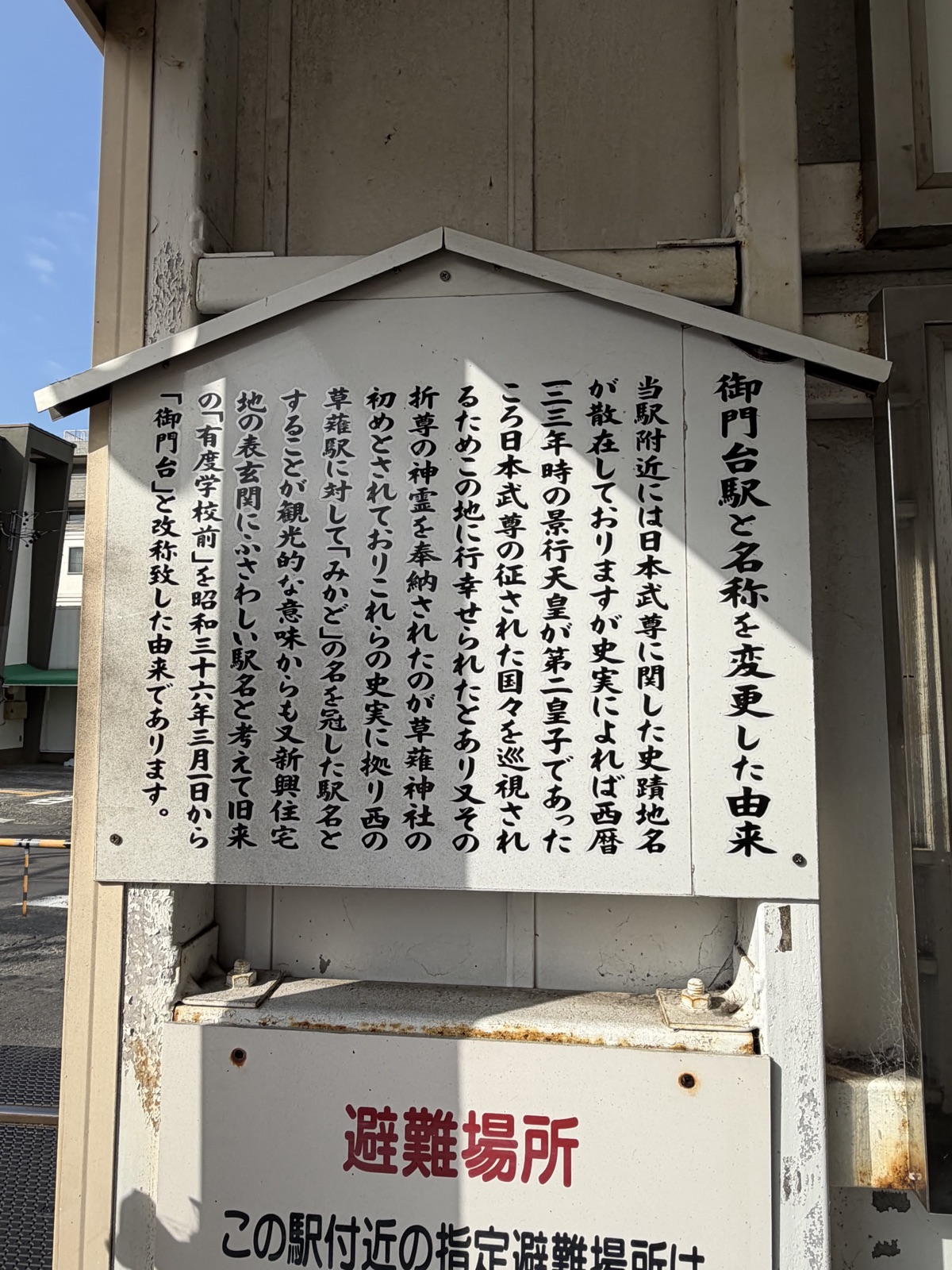 御門台駅のホームに立つ、駅名の由来を書いた木の説明板