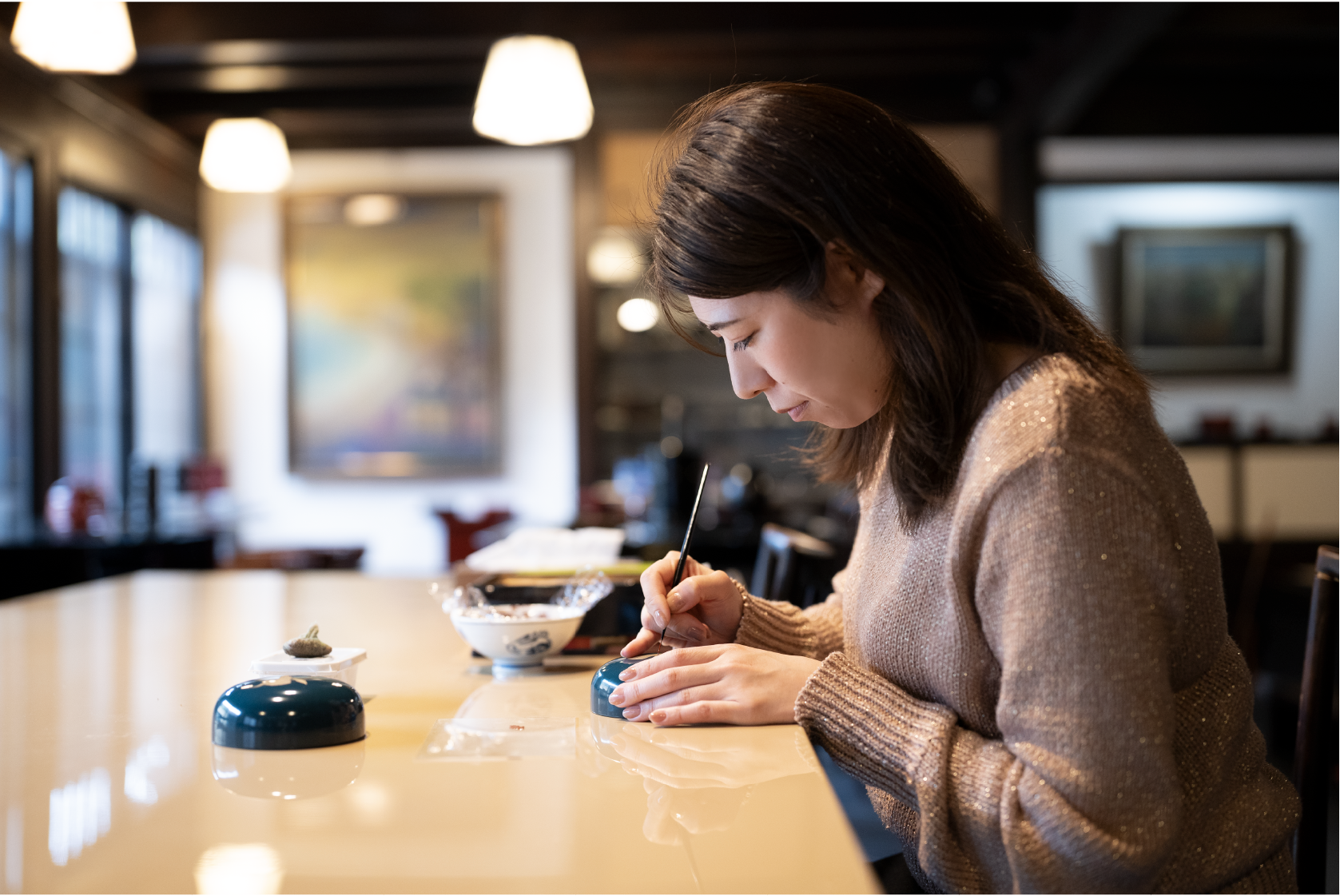 ボンボニエールという菓子器に蒔絵を描く希望さん。 蒔絵用の筆を使って均一に線を引いていく